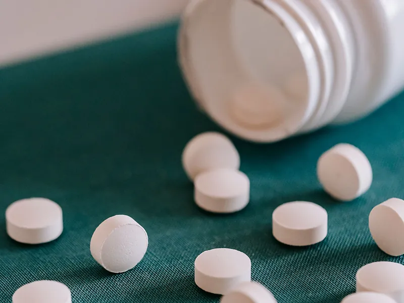 White tablets beside an open medicine bottle – pharmaceuticals supplied by Tibleino General Trading
